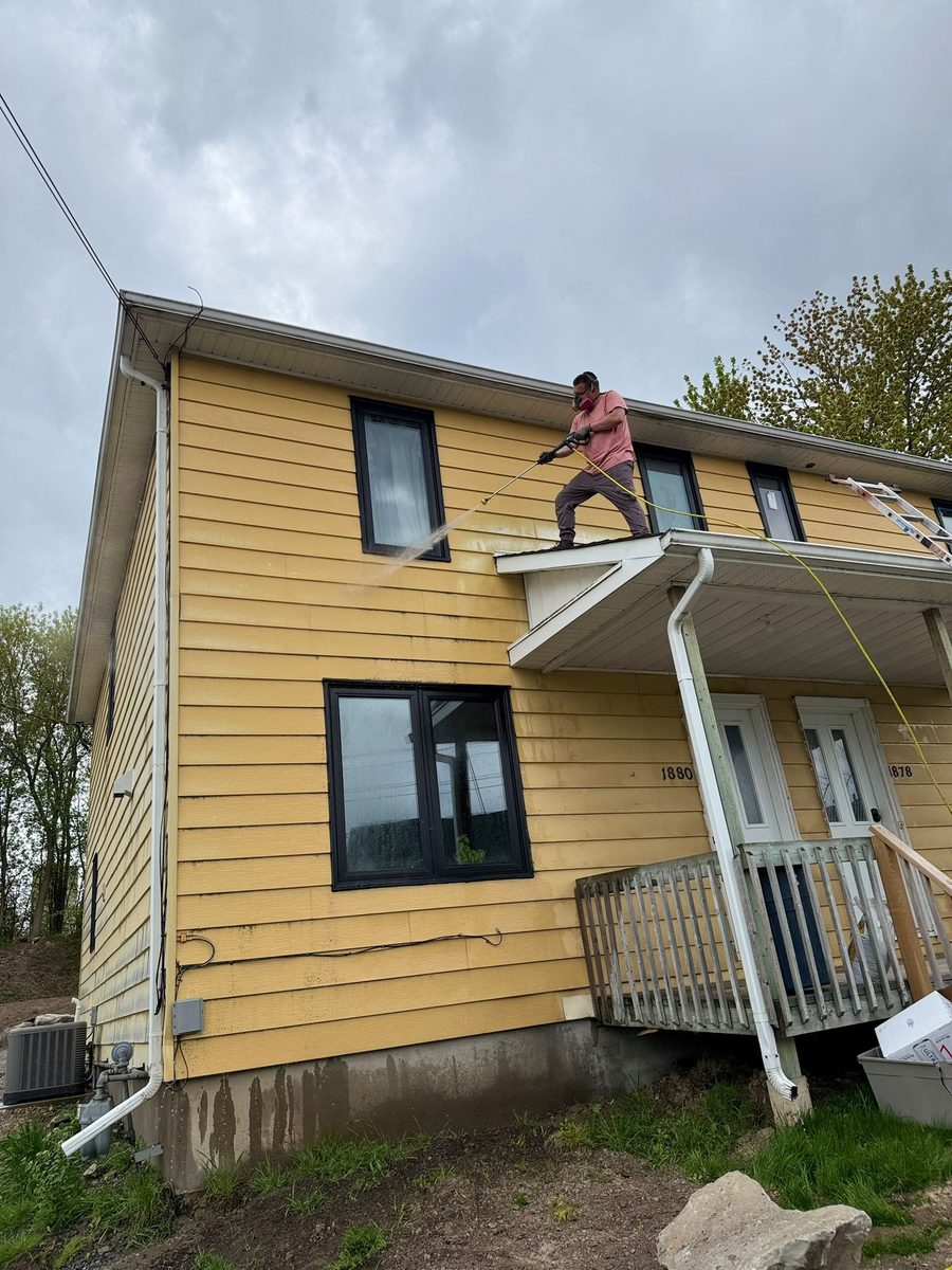 Refinishing a home exterior on a ladder
